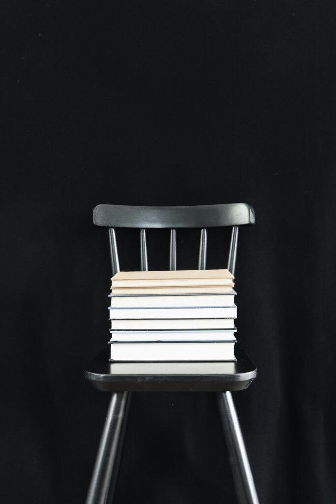 Stack of books in a black chair.